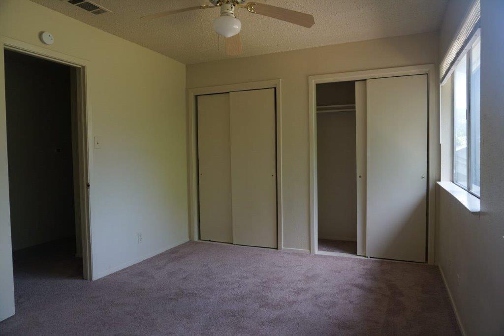 5919 Hidden Valley Trail Austin, TX 78744 - Photo 6 of 8 A comfortable bedroom features plush carpeting, two convenient closets, and a refreshing ceiling fan.