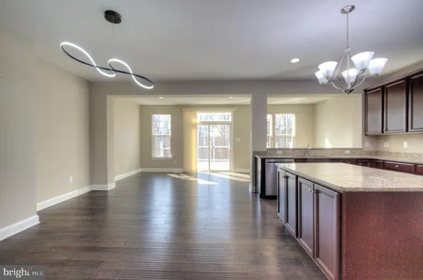 a kitchen with stainless steel appliances kitchen island granite countertop a refrigerator a sink dishwasher a stove and a dining table with wooden floor