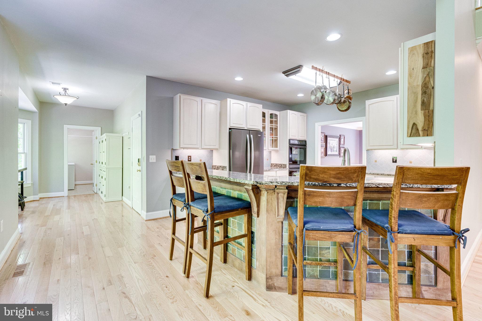 7802 Creekside View Lane Springfield, VA 22153 - Photo 21 of 107 a open kitchen with stainless steel appliances kitchen island granite countertop a dining table chairs and white cabinets