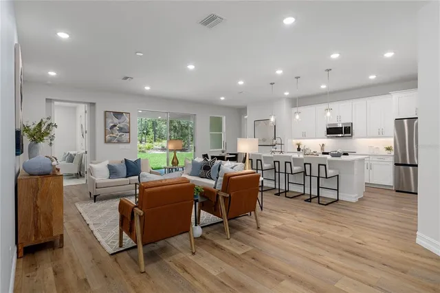 a living room with stainless steel appliances kitchen island granite countertop furniture wooden floor and a view of kitchen