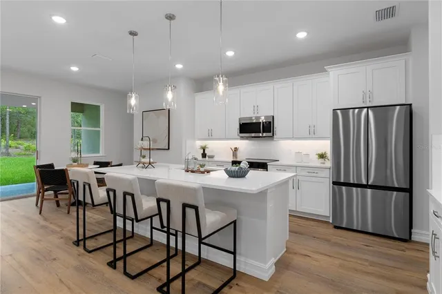 a kitchen with stainless steel appliances granite countertop a dining table chairs refrigerator and cabinets
