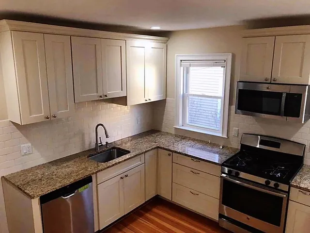 a kitchen with granite countertop a sink stove and cabinets