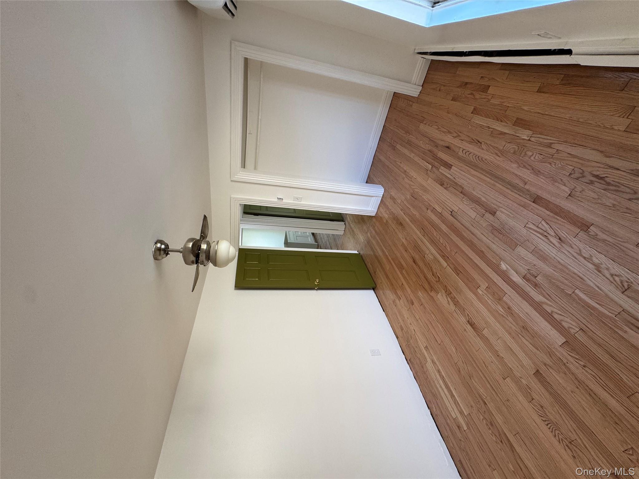103-14 169th Street Queens, NY 11433 - Photo 12 of 18 Unfurnished bedroom featuring light wood-style floors, ceiling fan, a closet, and a wall unit AC