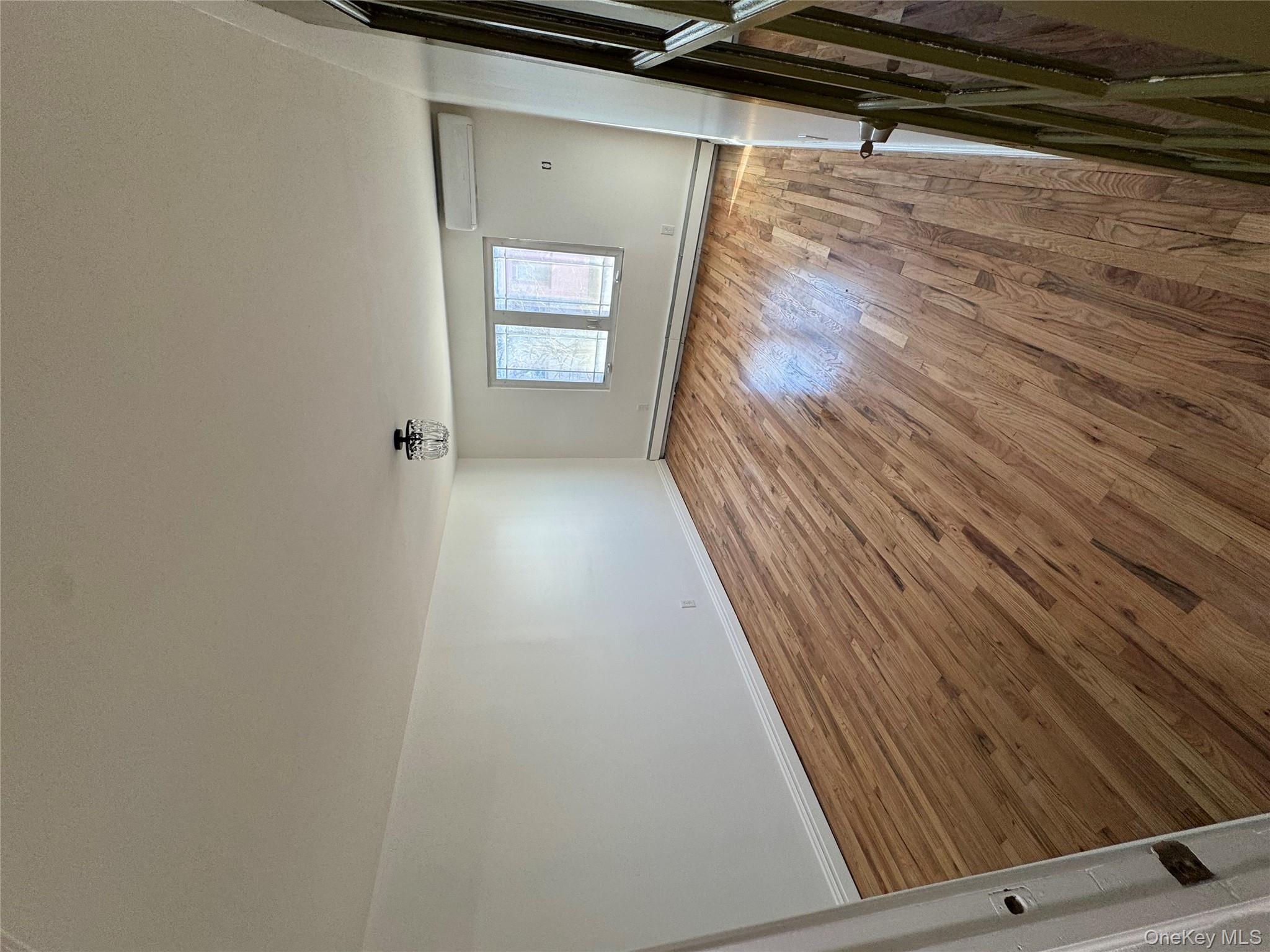 103-14 169th Street Queens, NY 11433 - Photo 15 of 18 Unfurnished room featuring light wood finished floors, a baseboard heating unit, and a wall mounted AC