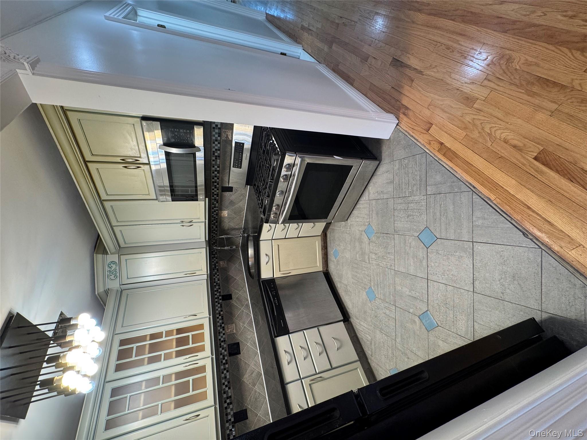 103-14 169th Street Queens, NY 11433 - Photo 7 of 18 Kitchen featuring stainless steel range, dark countertops, glass insert cabinets, dishwasher, and light wood finished floors