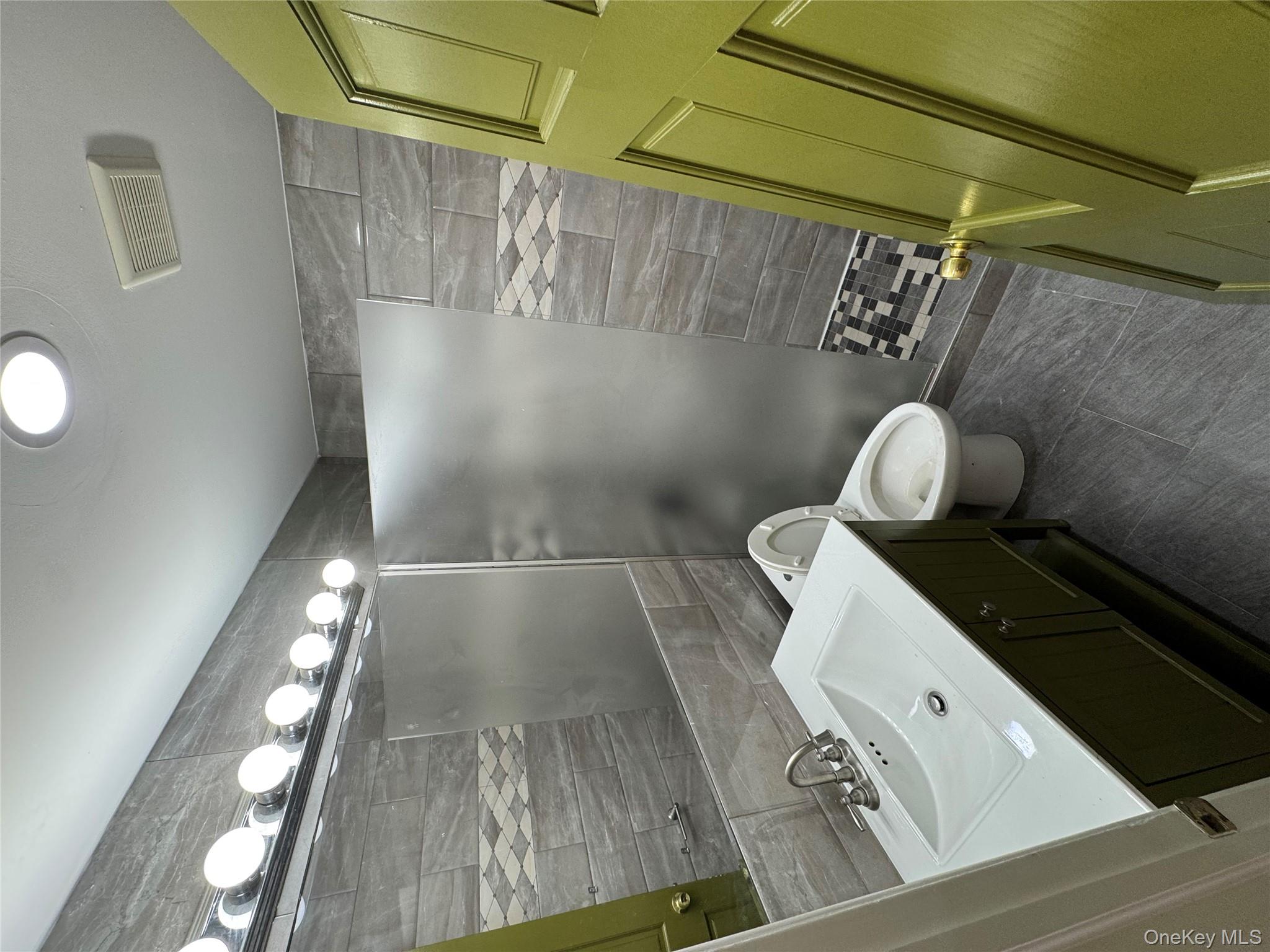 103-14 169th Street Queens, NY 11433 - Photo 9 of 18 Full bath featuring vanity, walk in shower, tile walls, and dark tile patterned flooring