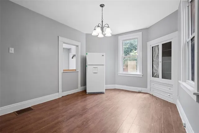 an empty room with wooden floor chandelier and windows