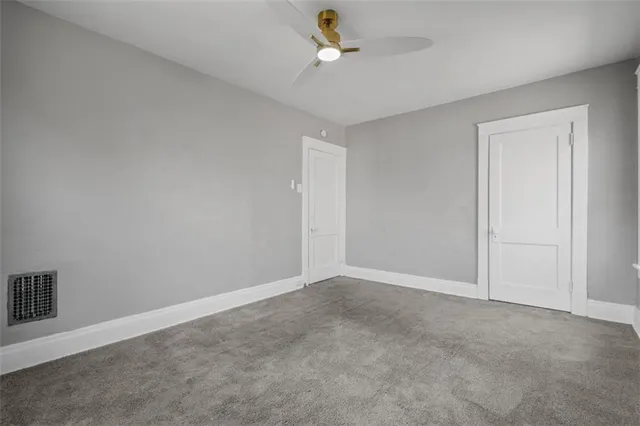 an empty room with ceiling fan and window
