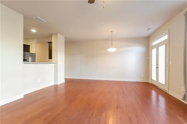 a view of an empty room with wooden floor and a window