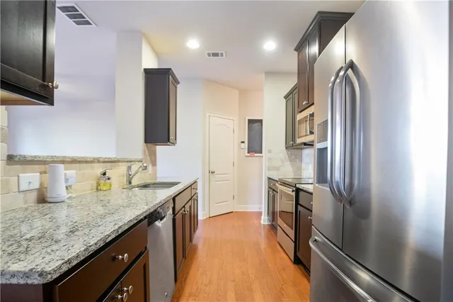 a kitchen with stainless steel appliances granite countertop a refrigerator and a sink
