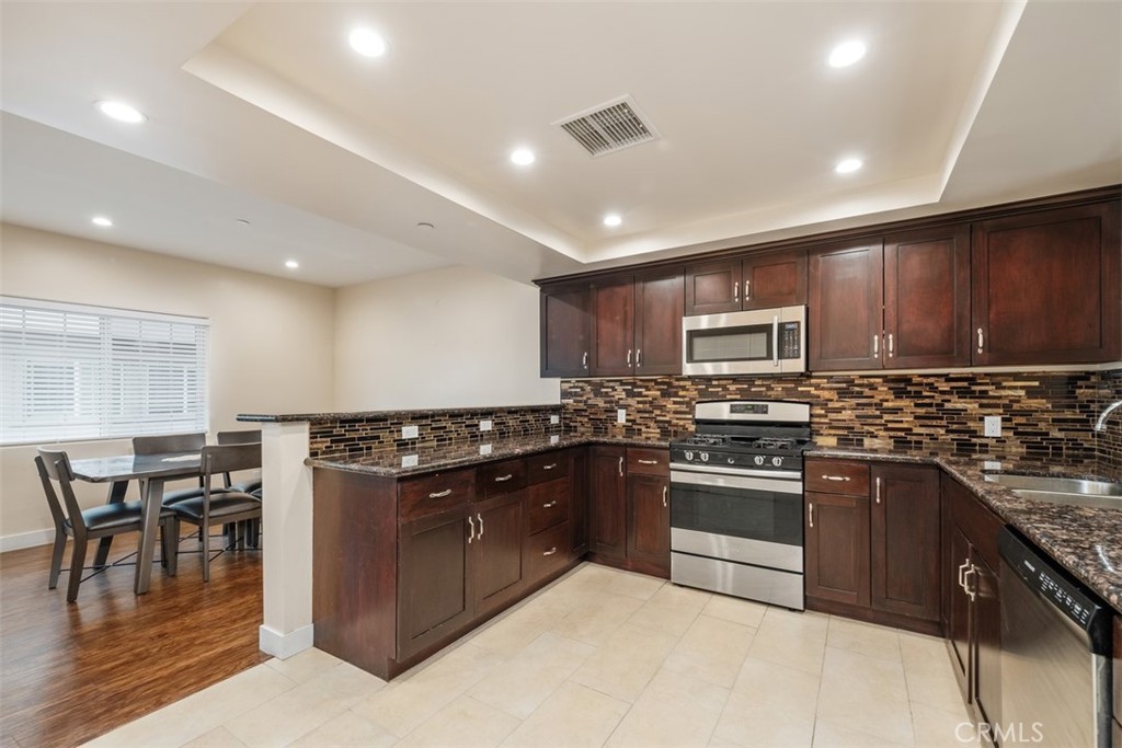 900 Dwight Avenue, Unit 108 Compton, CA 90220 - Photo 13 of 49 a kitchen with stainless steel appliances granite countertop wooden cabinets a sink a stove a dining table and chairs