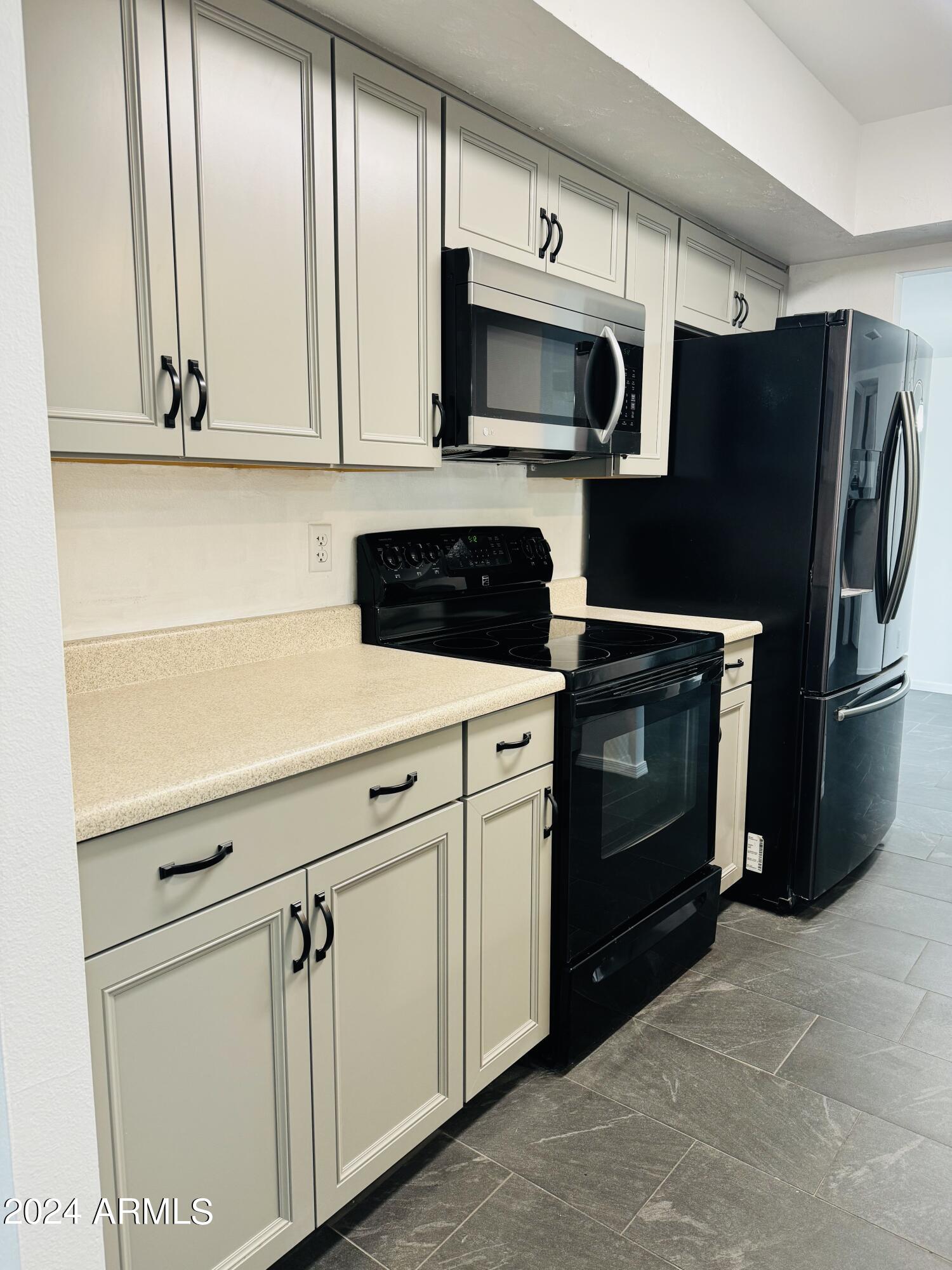 1216 East Riviera Drive Tempe, AZ 85282 - Photo 11 of 33 a kitchen with stainless steel appliances white cabinets a stove a microwave and a refrigerator