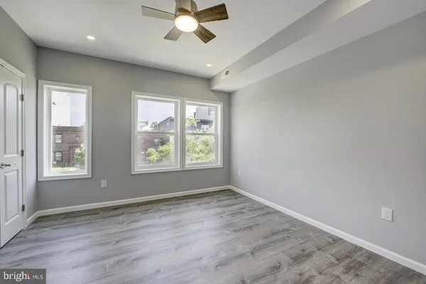 a view of an empty room with a window and wooden floor