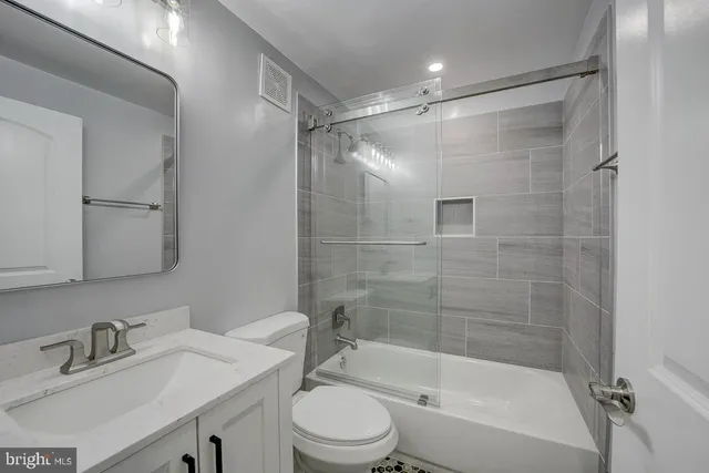 a bathroom with a bathtub shower sink vanity and toilet