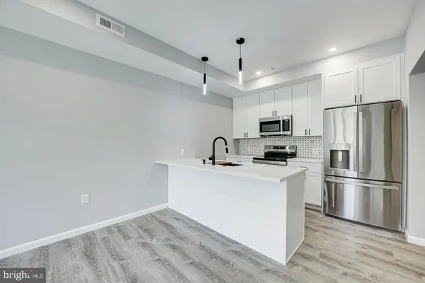 a kitchen with stainless steel appliances a refrigerator stove a sink and white cabinets