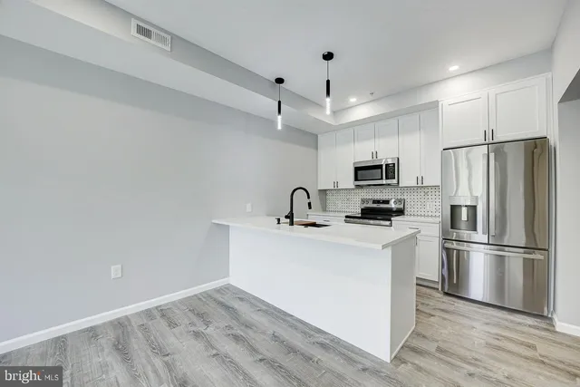 a kitchen with stainless steel appliances a refrigerator stove a sink and white cabinets