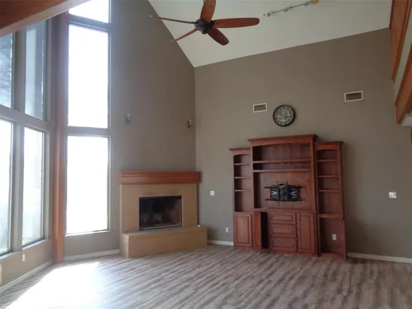 an empty room with wooden floor a fireplace and windows