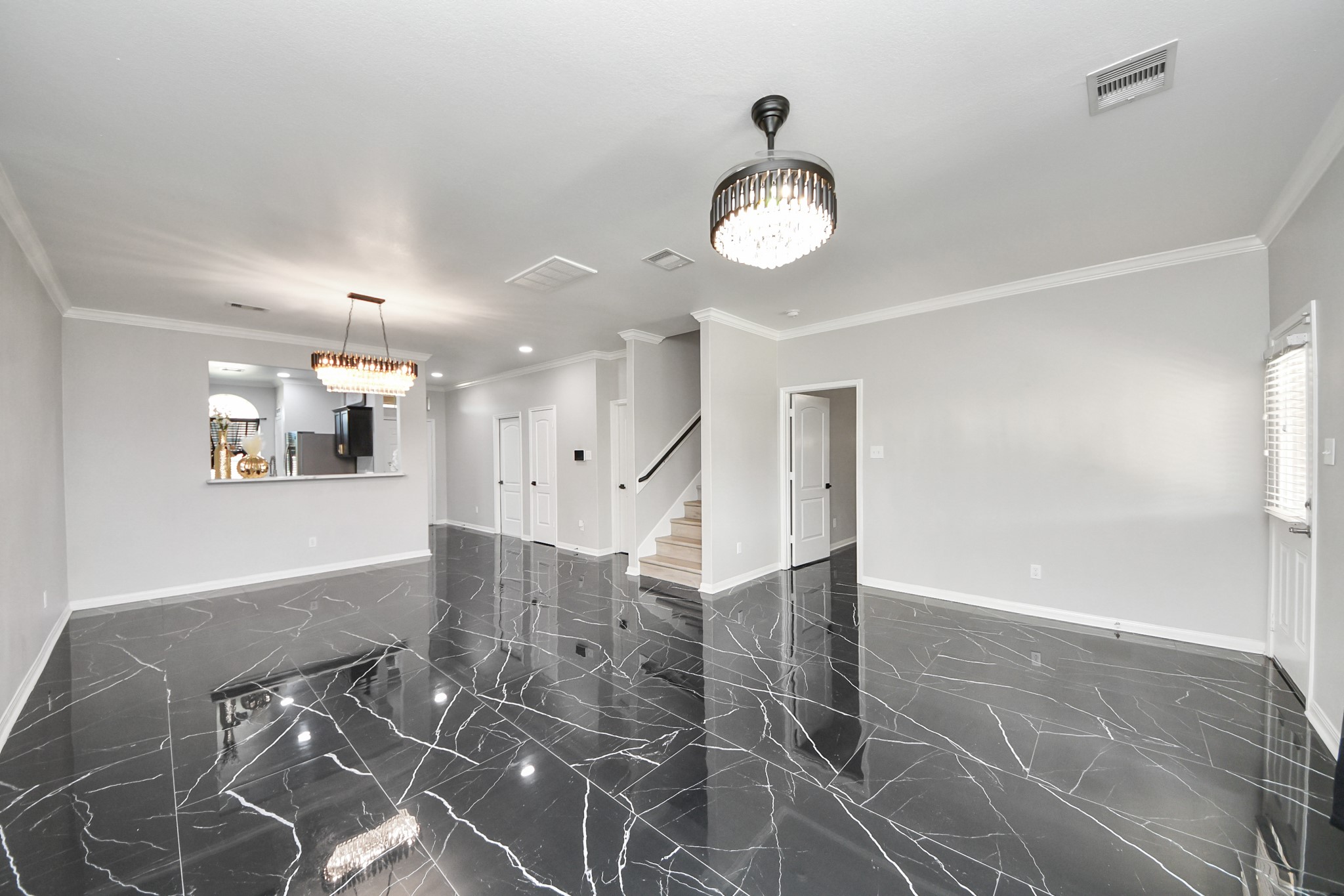 6931 Primrose Road Baytown, TX 77521 - Photo 14 of 50 Spacious open-concept living room with modern chandeliers and sleek marble tile flooring.