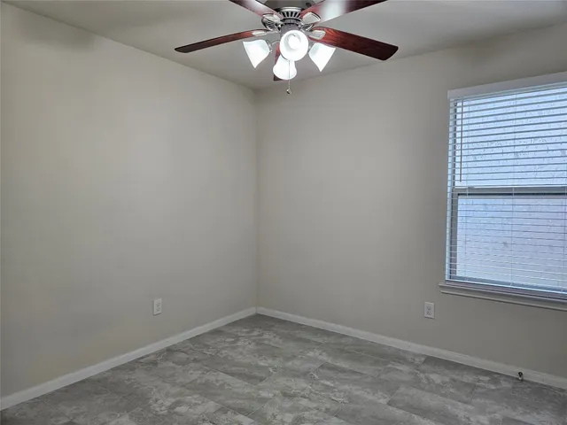 an empty room with a window and a fan