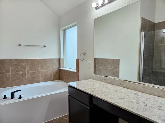 a bathroom with a granite countertop bathtub sink and mirror