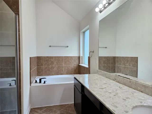 a bathroom with a granite countertop bathtub sink and mirror