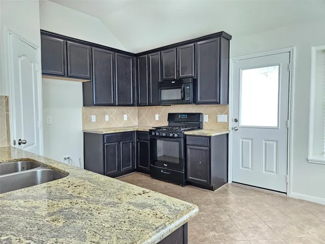 a kitchen with stainless steel appliances granite countertop a refrigerator a stove a sink and a oven