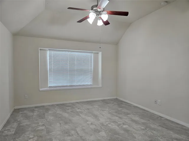 an empty room with a chandelier fan and windows