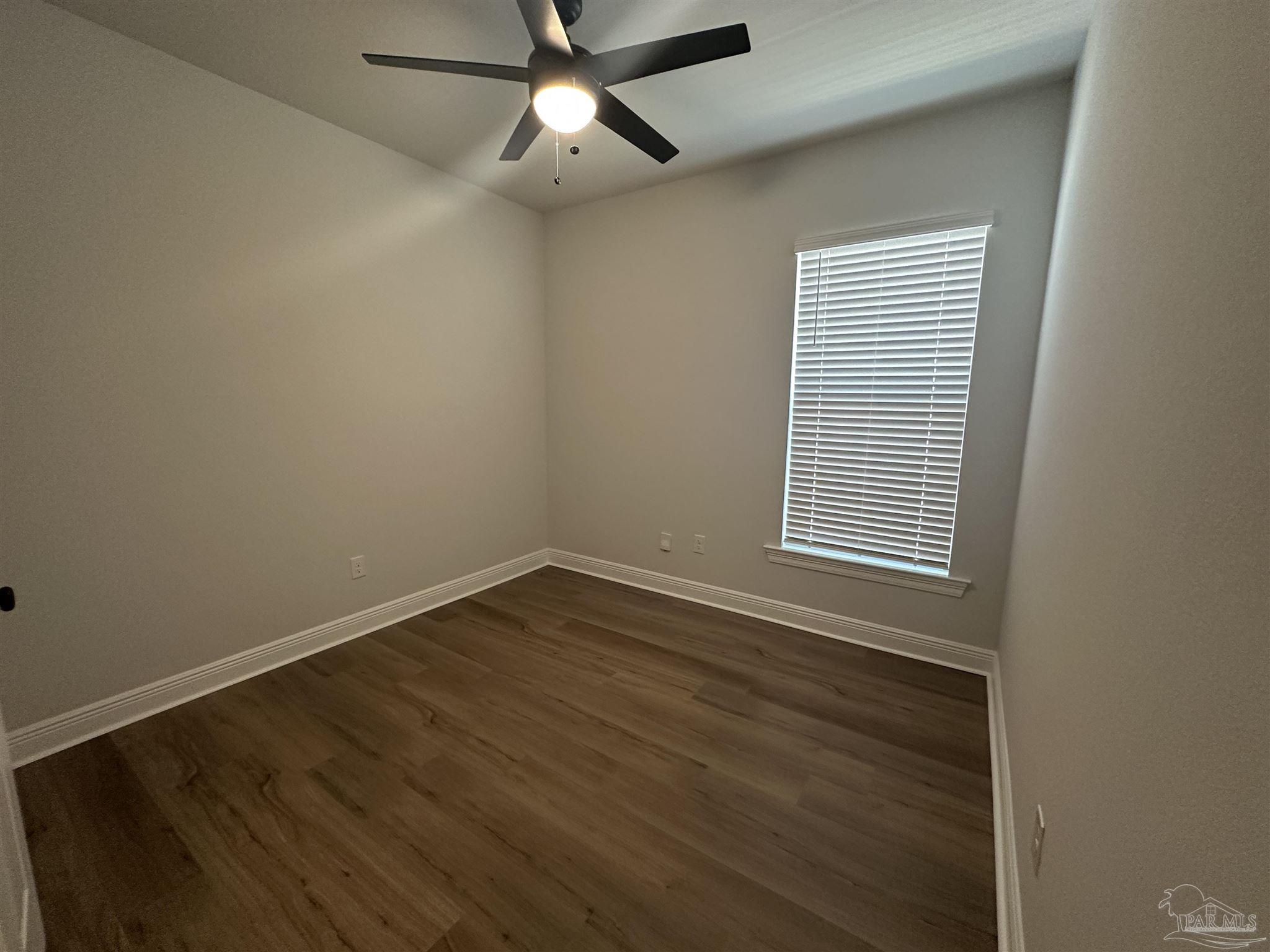 4753 Sago Palm Circle Pace, FL 32571 - Photo 18 of 24 an empty room with wooden floor fan and windows