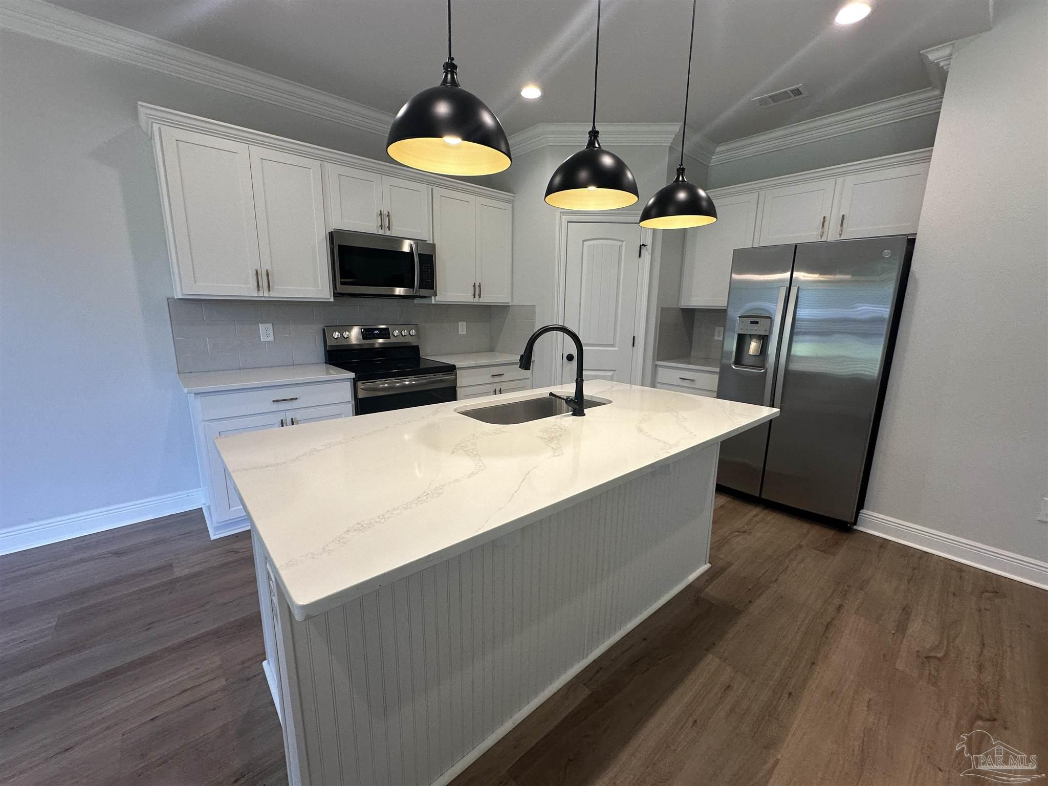 4753 Sago Palm Circle Pace, FL 32571 - Photo 5 of 24 a kitchen with stainless steel appliances a table chairs and a chandelier