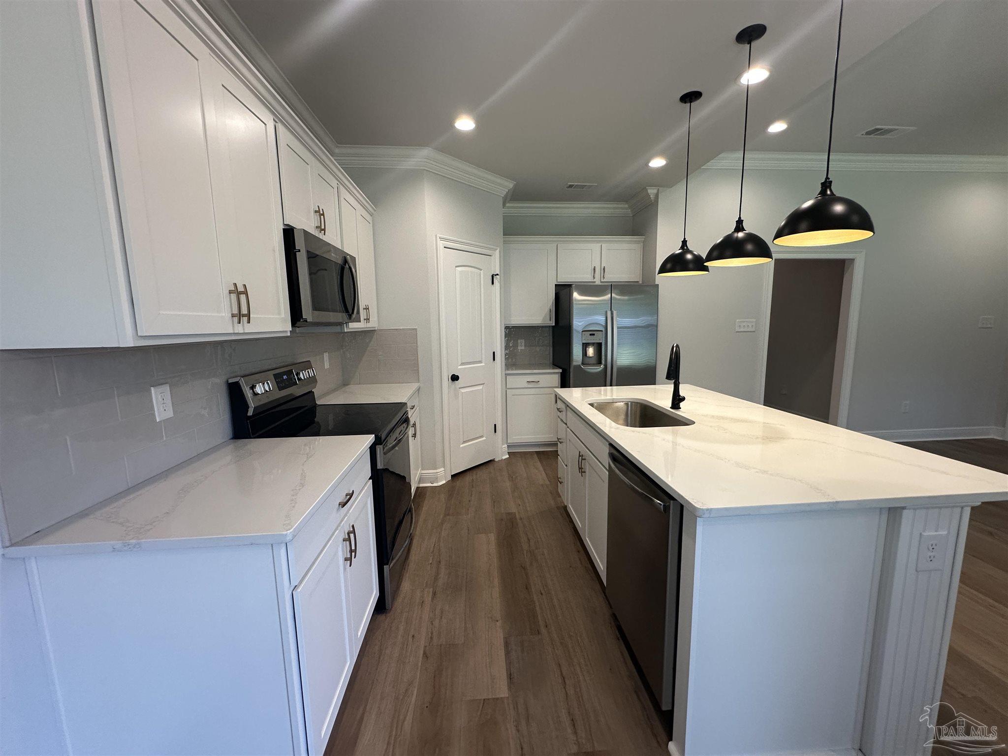 4753 Sago Palm Circle Pace, FL 32571 - Photo 6 of 24 a kitchen with a sink a counter top space stainless steel appliances and cabinets