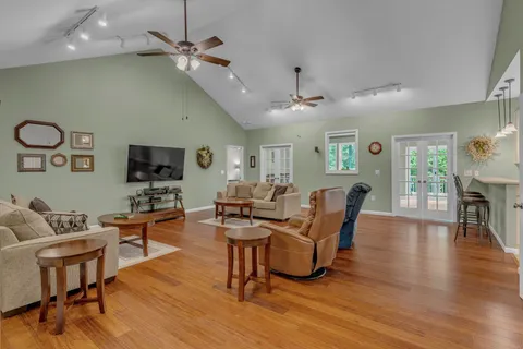 a living room with furniture kitchen view and a wooden floor