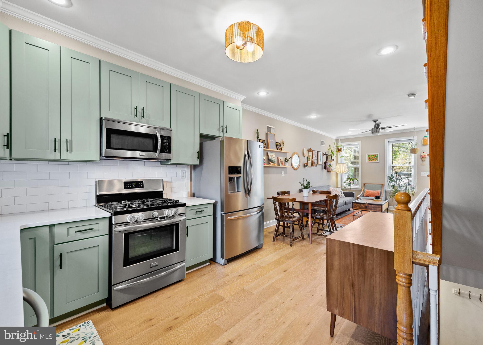 623 Manton Street Philadelphia, PA 19147 - Photo 8 of 26 a kitchen with stainless steel appliances granite countertop a stove top oven a refrigerator and a dining table with wooden floor