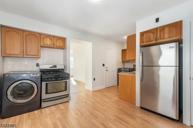 a kitchen with a refrigerator a stove top oven and wooden floor