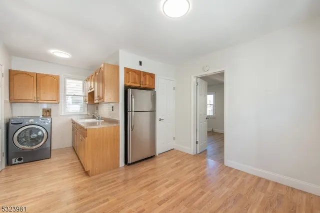 a view of a kitchen with fridge and wooden floor