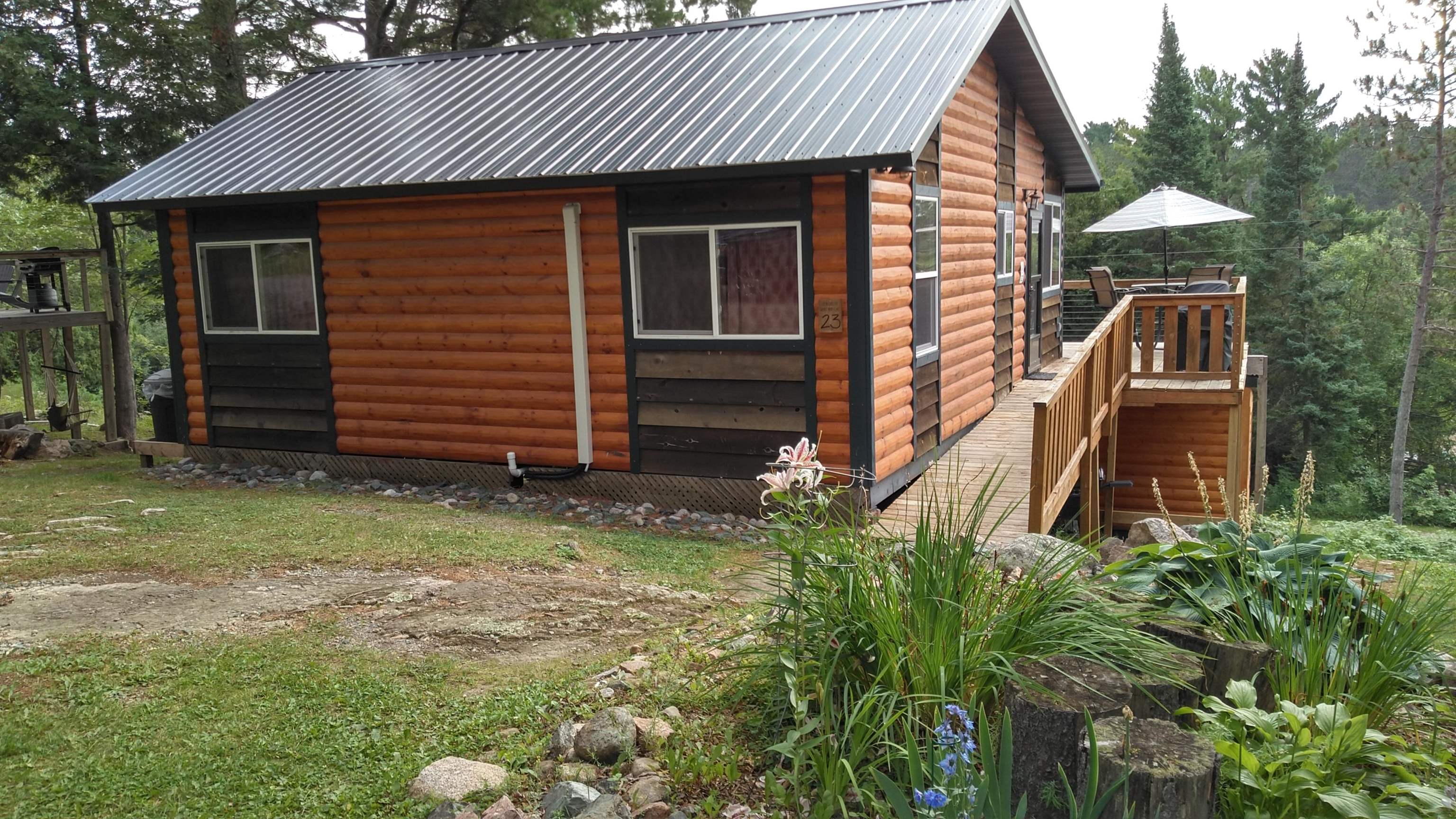 View of side of home with faux log siding, a deck, and a metal roof