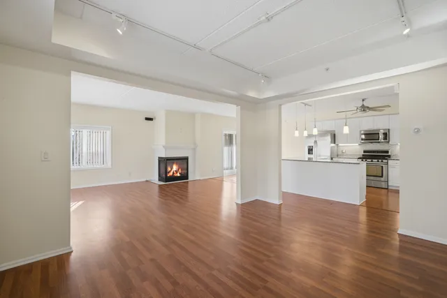 a view of a kitchen and an empty room with wooden floor