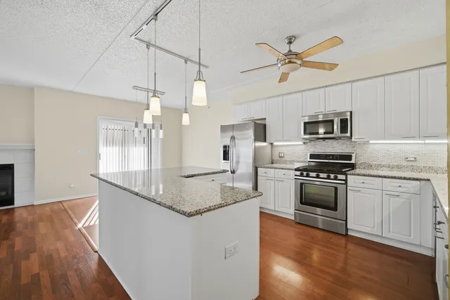 a kitchen with granite countertop a stove a sink and a refrigerator