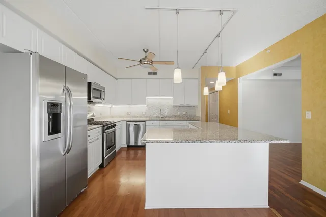 a large kitchen with stainless steel appliances a large counter top a stove a sink dishwasher and a refrigerator