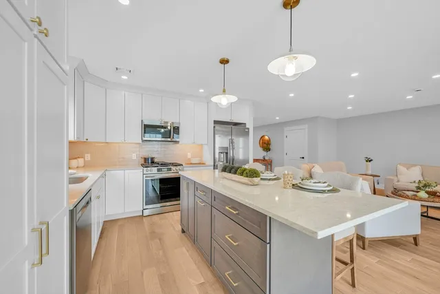 a kitchen with a stove a sink a kitchen island with white cabinets and wooden floor