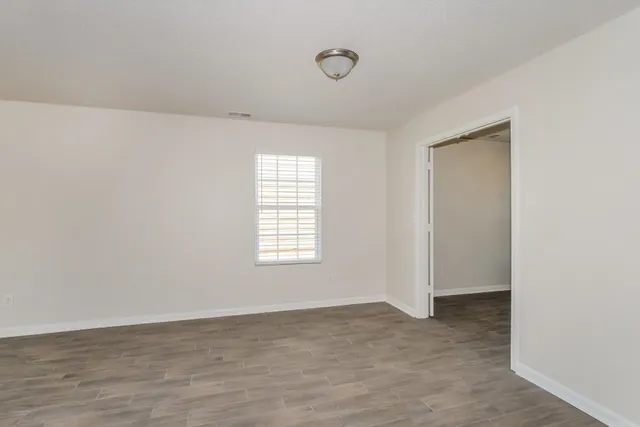 an empty room with chandelier fan and windows