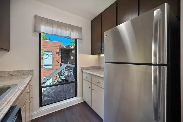 a kitchen with granite countertop stainless steel appliances a sink a stove cabinets and wooden floor