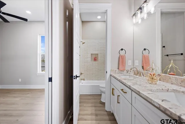 a bathroom with a granite countertop double vanity sink a mirror and a bathtub