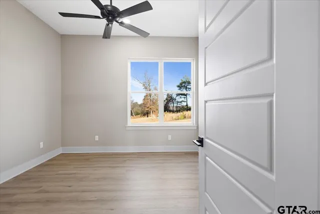 an empty room with windows and fan