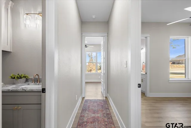 a view of a hallway with wooden floor and a bathroom