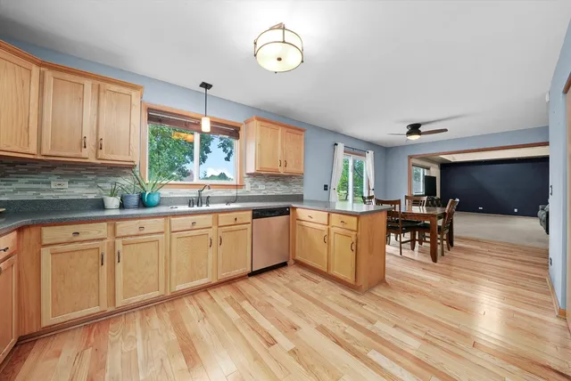 a kitchen with stainless steel appliances granite countertop a stove a sink dishwasher and white cabinets with wooden floor