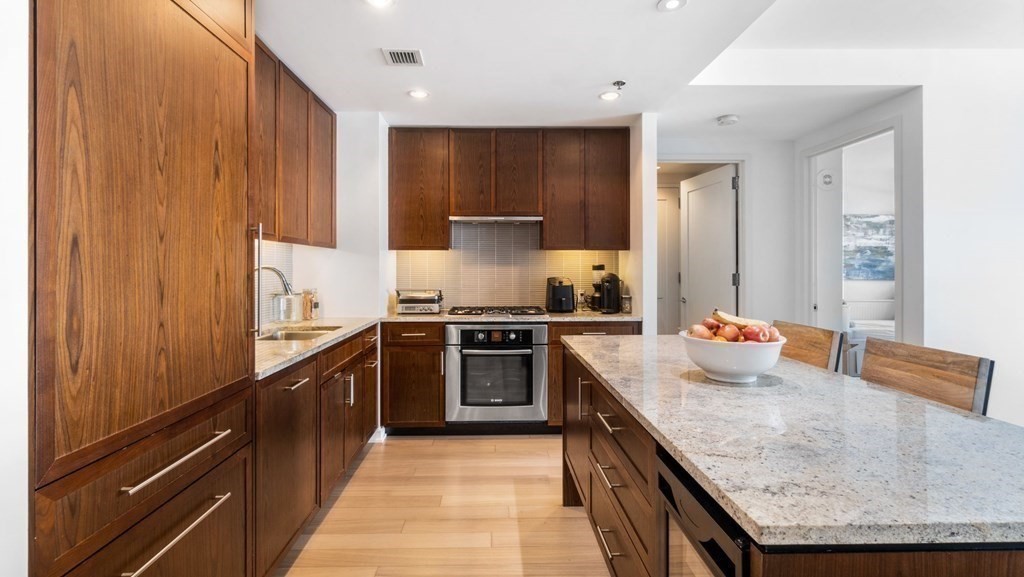 a kitchen with stainless steel appliances granite countertop wooden cabinets and a stove