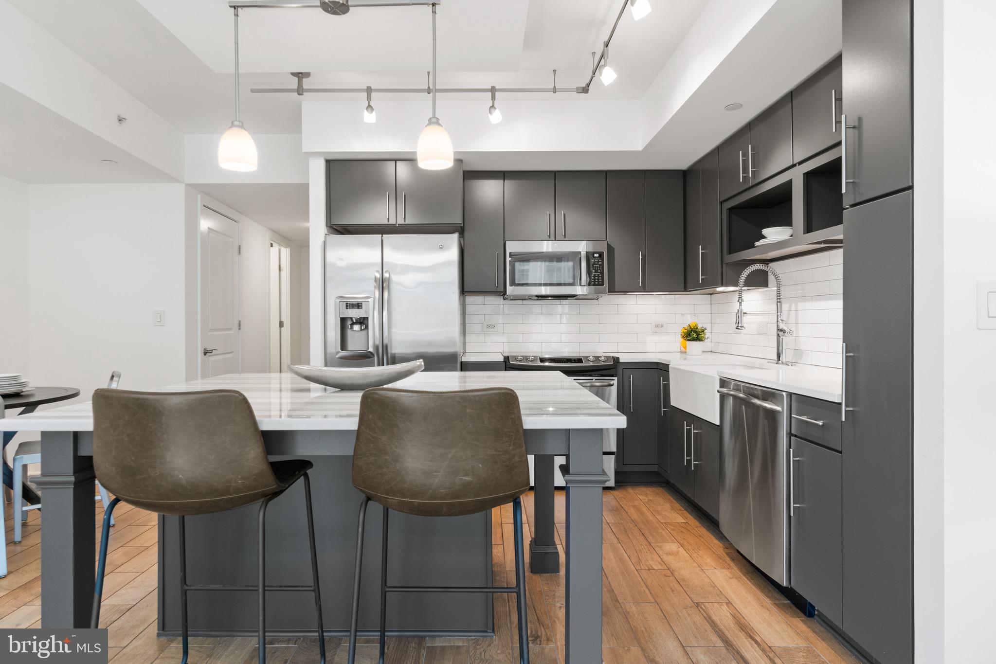 1025 First Street Southeast, Unit 1010 Washington, DC 20003 - Photo 11 of 36 a kitchen with kitchen island granite countertop a sink cabinets and stainless steel appliances