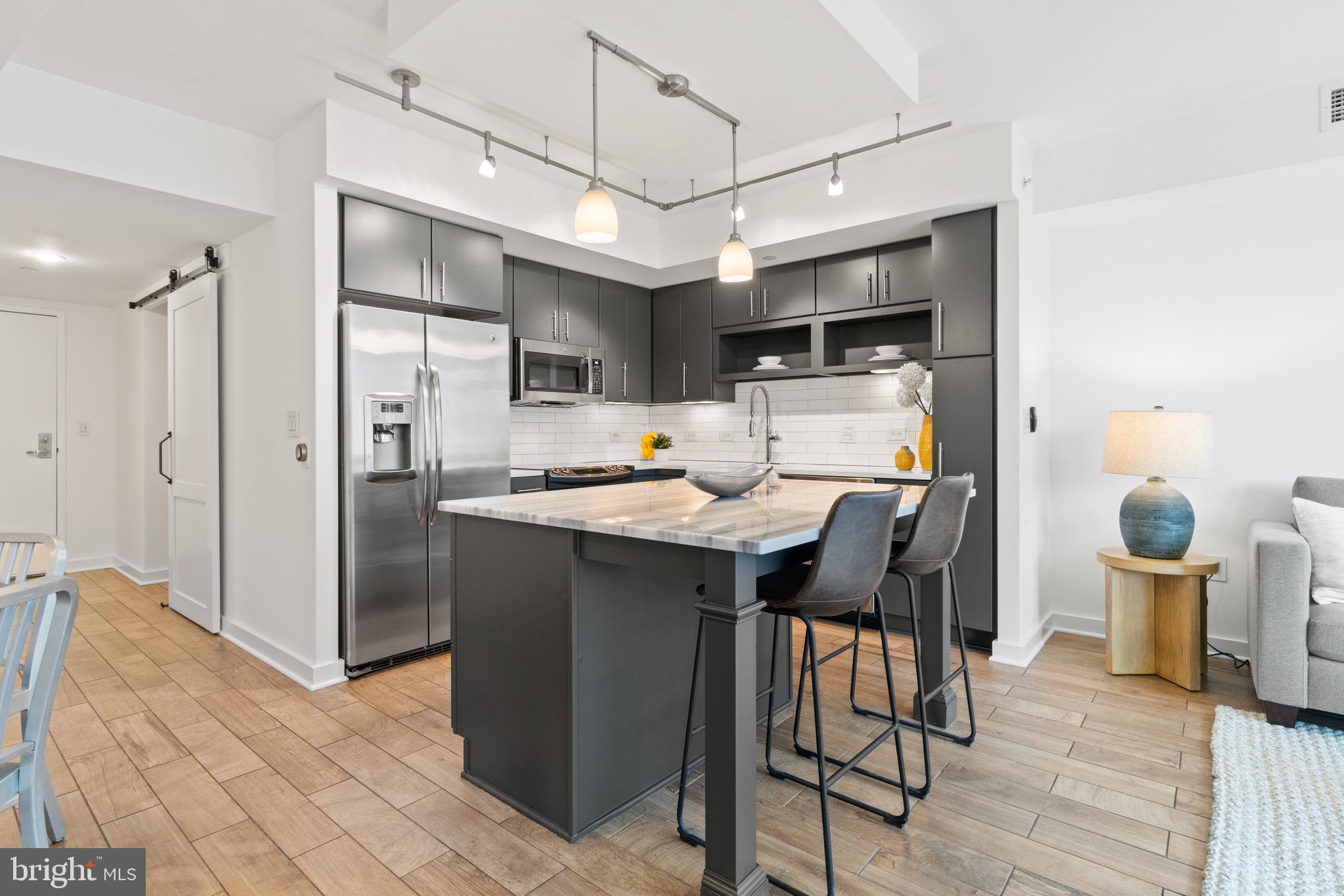 1025 First Street Southeast, Unit 1010 Washington, DC 20003 - Photo 9 of 36 a kitchen with stainless steel appliances kitchen island granite countertop a refrigerator and a stove