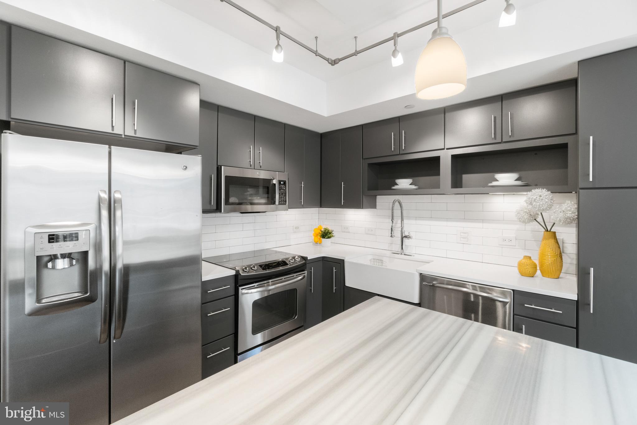 1025 First Street Southeast, Unit 1010 Washington, DC 20003 - Photo 10 of 36 a kitchen with stainless steel appliances kitchen island granite countertop a refrigerator a sink a stove and oven