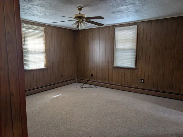 an empty room with windows and fan